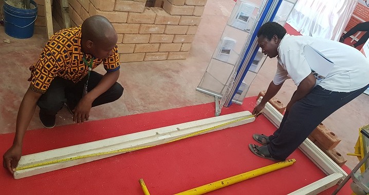 Mwananchi akipima urefu wa fremu ya zege ya mlango alipotembelea banda la NHBRA katika maonesho ya Sabasaba