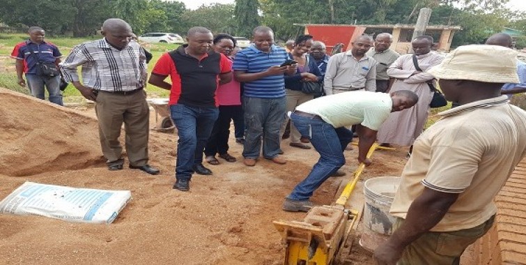 Washiriki wa semina ya ''Adequate Housing'' kutoka Uganda, Kenya, Mozambique na  Zambia wakifanya majaribio ya kufyatua tofali la kufungamana walipotembelea ofisi za NHBRA